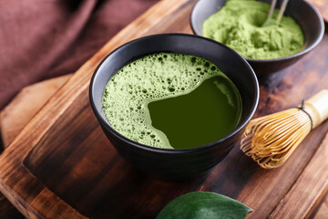 Tray with bowl of matcha tea, powder and chasen on table, closeup