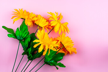 orange plastic flowers on pink background copy space greeting card background