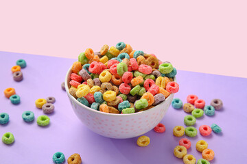 Bowl with tasty cereal rings on color background