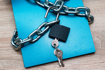 a writing pad wrapped in an iron chain with an open lock with keys information protection concept data protection
