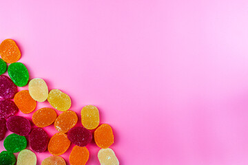 colorful marmalade candies in the lower left corner on a pink background background postcard