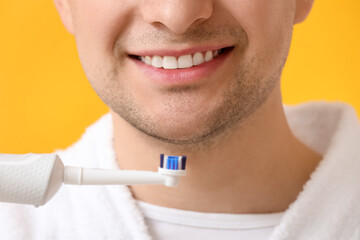 Man brushing teeth on color background, closeup