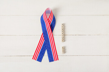 Text MEMORIAL DAY and ribbon in colors of USA flag on white wooden background