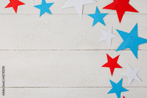 Paper stars in colors of USA flag on white wooden background