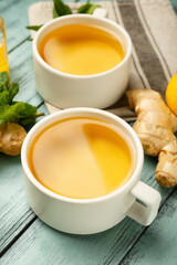 Cups of tea with ginger and lemon on color wooden background