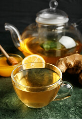 Teapot and cup of tea with ginger, honey and lemon, closeup