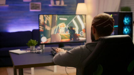 Pro gamer playing first person shooter video game at gaming home studio using RGB mouse keyboard. Virtual online streaming setup with neon lights cyber performing during game tournament