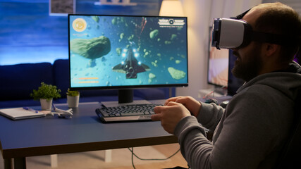 Competitive gamer winning space shooter video games championship wearing virtual reality goggles. Pro cyber professional playing with joypad during online tournament using technology network wireless © DC Studio