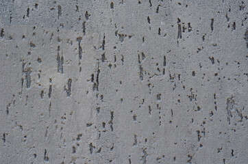 A gray concrete wall with small dark depressions.