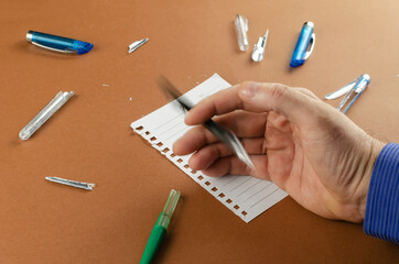 Motion blur. Adult man nervously plays with pen over brown desk.