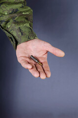 A middle-aged man's hand with automatic rifle ammunition on a gr