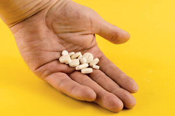 Hand and medical pills on a yellow background.