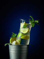 Mojito cocktail with ice, lime, and mint in a bucket with ice.