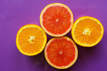 Composition with orange and grapefruit slices on a purple background.