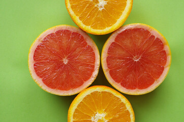 Composition with orange and grapefruit slices on a green background.