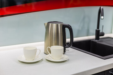 Steel teapot with cups in the kitchen.