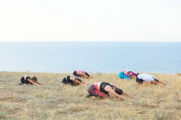 Instructor trains yoga kids in the mountains on the ocean.