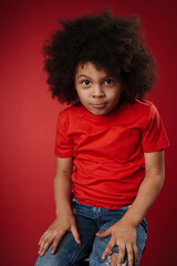 Smiling little child in everyday clothes over wall background