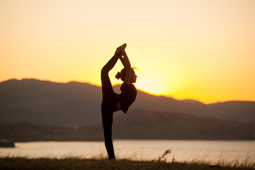 Girl practices yoga in the mountains on the ocean.