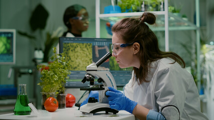 Scientist doctor analyzing botanical plants under microscope for chemical test. Biologist...