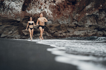 Elegant couple on a beach near rocks