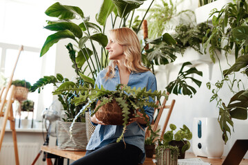 Portrait of a careful young woman with houseplant sitting on table