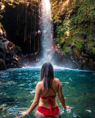 woman in beautiful waterfall with red bikini