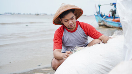 Portrait of a young male fisherman preparing a fishing net in beach