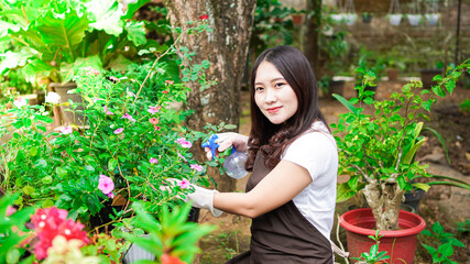 Asian woman taking care watering flower at home garden