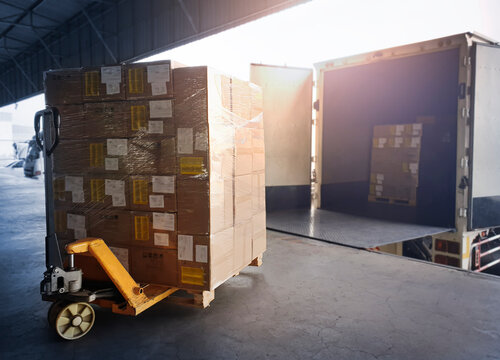 Package Boxes Loading into Container Truck. Truck Parked Loading at Dock Warehouse. Delivery Service. Shipping Warehouse Logistics. Shipment Freight Truck Transportation.	