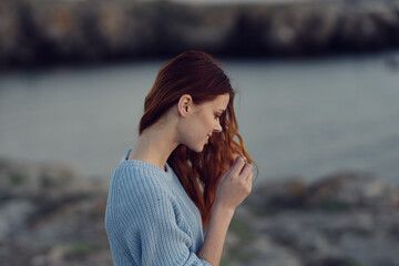 red-haired woman in a blue sweater near the river in nature