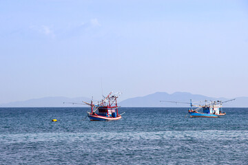 Traditional thai fishing boat floating in the sea of thailand near koh larn on day the bright sky.