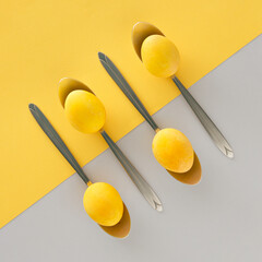 Easter eggs in a in spoons served on the table on a yellow and gray background. Minimal art top view. Easter festive creative composition.