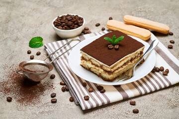 Fototapeta na wymiar Portion of Traditional Italian Tiramisu dessert and coffee beans on grey concrete background