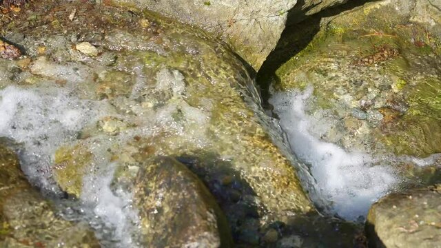 Front view of small waterfall, water surface flows over rocks 