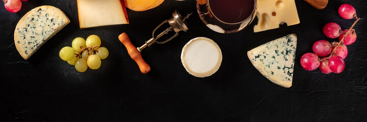Cheese and wine panorama, overhead flat lay shot on a black background