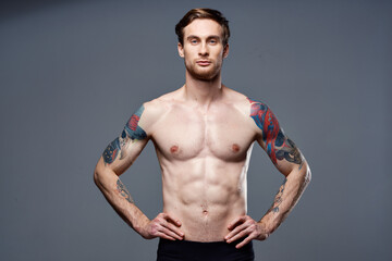 Fototapeta na wymiar sporty man tattoos on his arms naked torso bodybuilder gray background