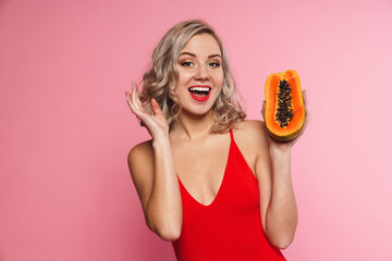 Happy young woman in swimsuit posing holding papaya