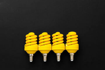 Yellow light bulbs on black background top view