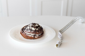 Slimming concept, bun with cream and waist meter