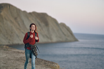 woman with a backpack on her back walks in nature near the sea in the mountains