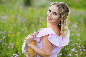 Young woman with a straw hat close-up on the background of the meadow.