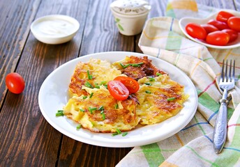 Potato fritters on a white plate on a wooden background. Jewish food.