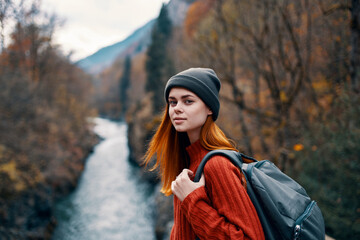 cheerful woman hiker in autumn clothes in the forest near the river