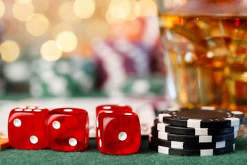 Game chips lie next to dice and glass of whiskey