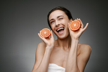 White laughing woman winking while posing with grapefruit