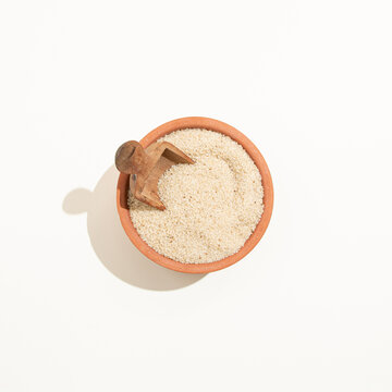 Minimalist earthy colors arrangement made of ancient cereal fonio millet whole grain in a clay pot on a pastel beige background. Flat lay organic healthy food harvest concept.