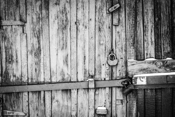 rusty lock on a texture of old, wooden, black and white door, which the old paint flaking. locked. place for text.