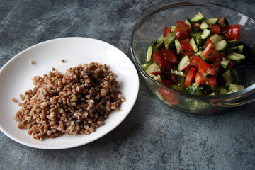 Buckwheat with a salad of tomatoes, cucumbers and dill with olive oil on a white plate. Vegetarianism. Lean food.
