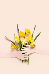 Bouquet of daffodils. Paper hands hold a bouquet of flowers on a pink background. Minimal. Copy space. Spring concept. Mothers day concept.